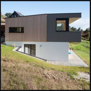 Modernes zweigeschossiges Haus mit Holzverkleidung am Hang und großem Fenster