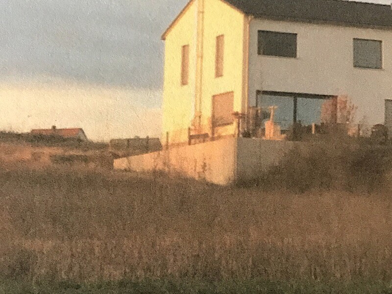 Aussenansicht eines modernen zweistoekigen hauses auf einem hang mit terrasse und gartenmauern