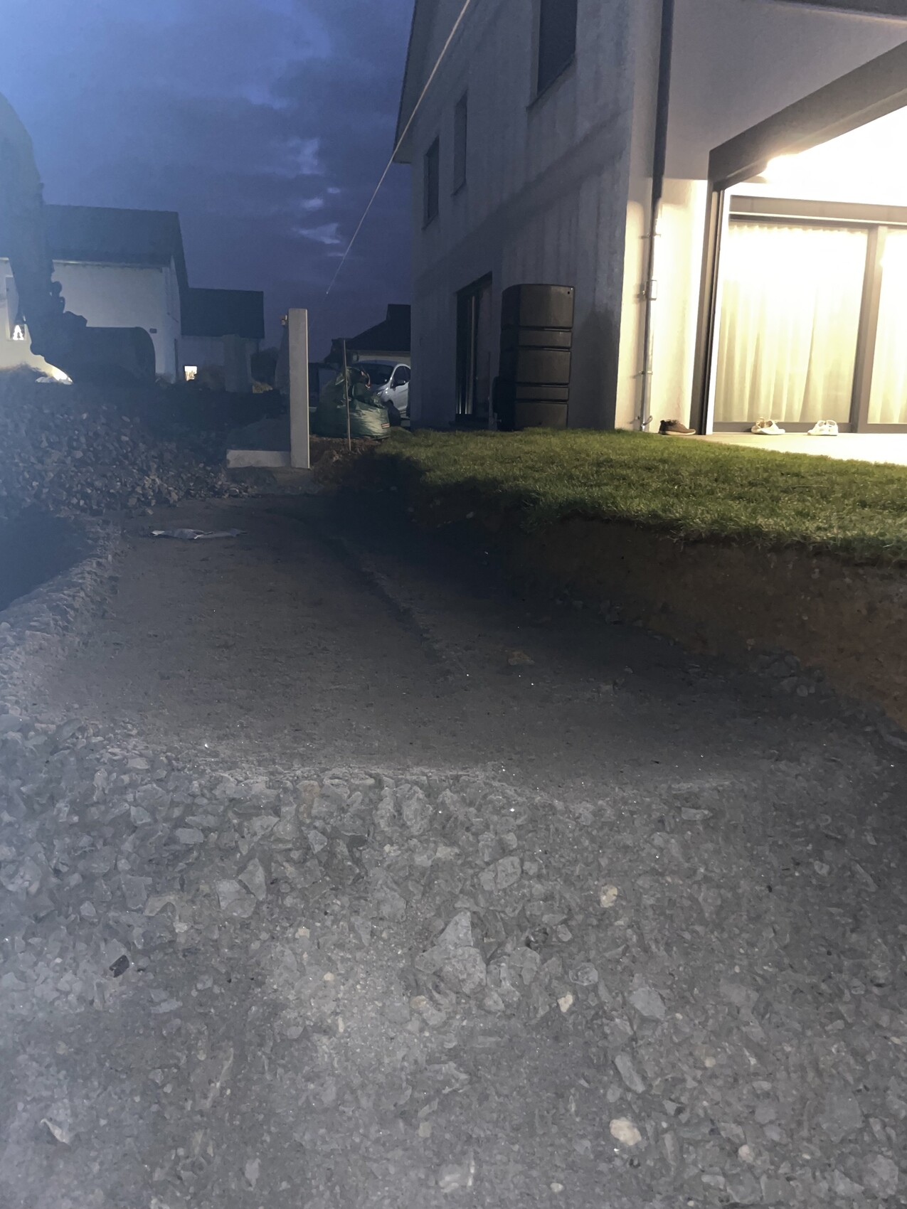 Nachtaufnahme eines modernen Hauses mit beleuchteter Glasfront und Kiesweg