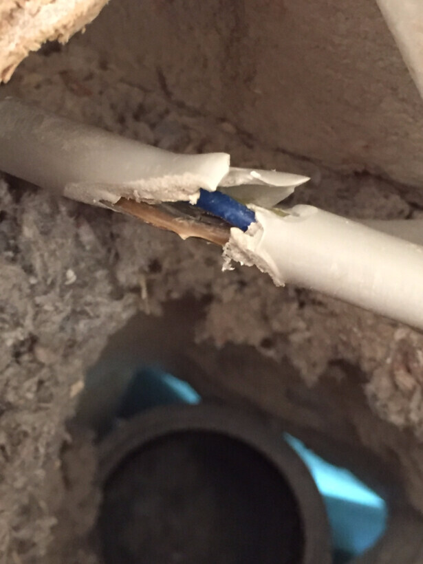 Nahaufnahme eines beschädigten Sanitaerrohrs mit freiliegendem Innenrohr auf Baustelle