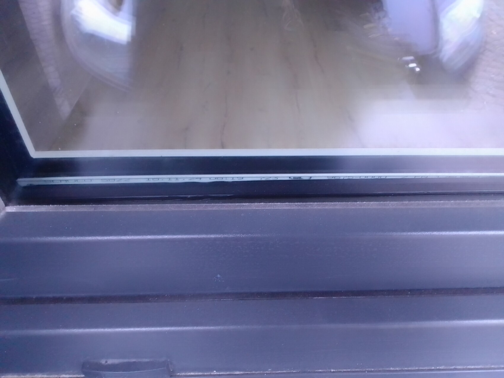 Nahaufnahme eines schwarzen Fensterrahmens mit Glas und Dichtung.