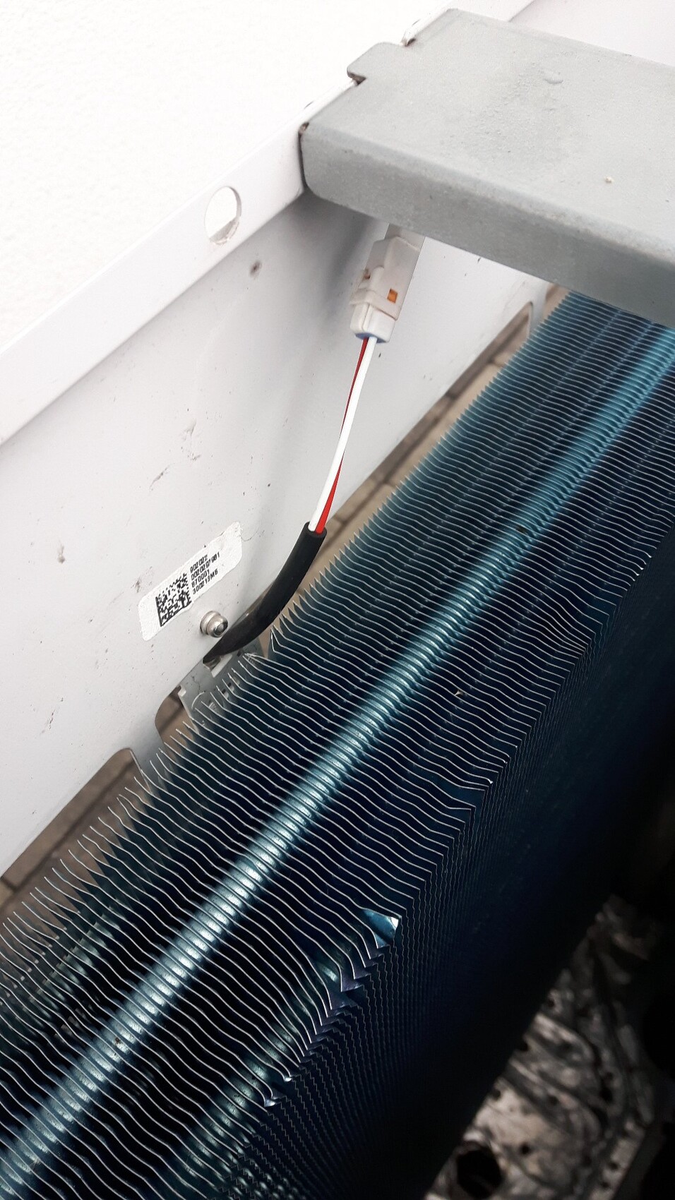 Nahaufnahme eines Wärmetauschers mit feinen Aluminiumlamellen und einem Steckverbinder