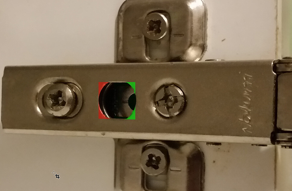 Nahaufnahme eines Türbandes aus Metall mit Schrauben und einem runden Loch in der Mitte.