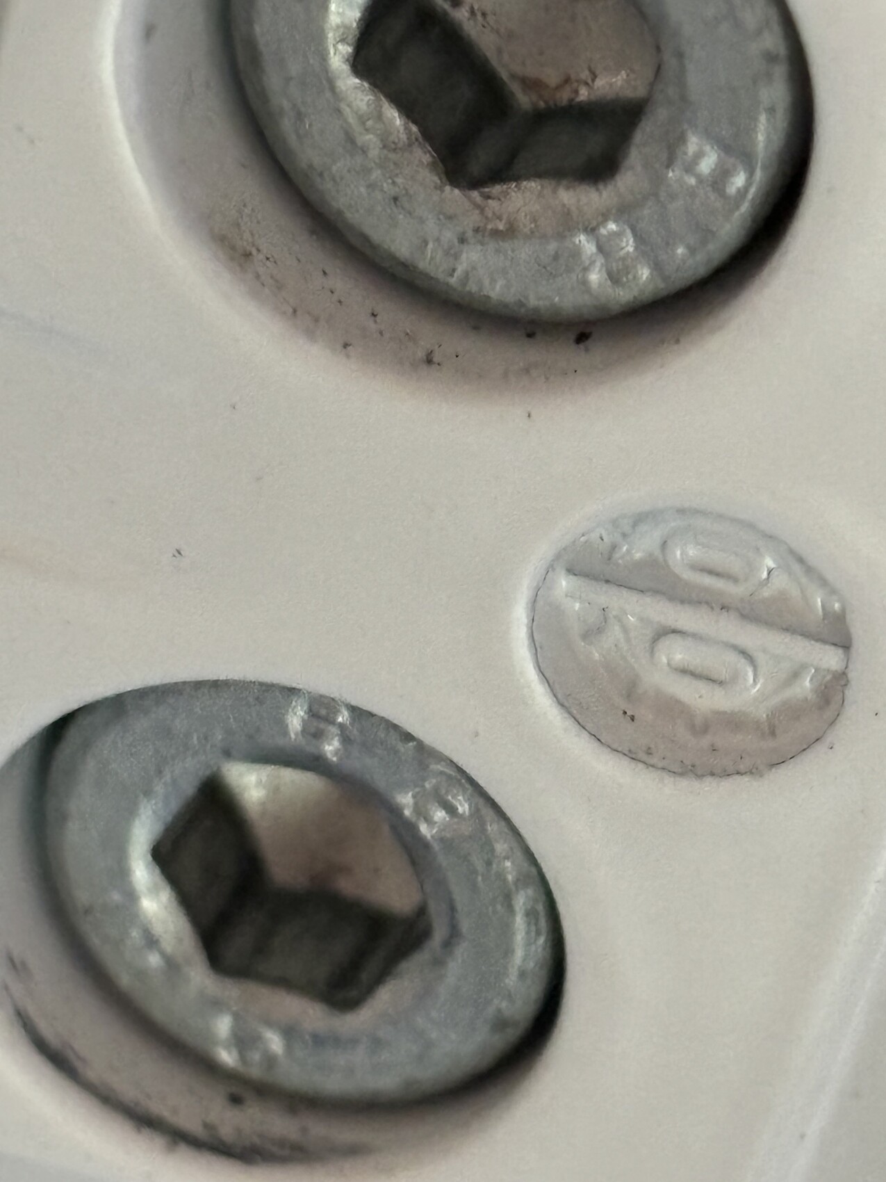 Nahaufnahme zweier Metallschrauben in heller Platte, Innensechskant-Kopf sichtbar