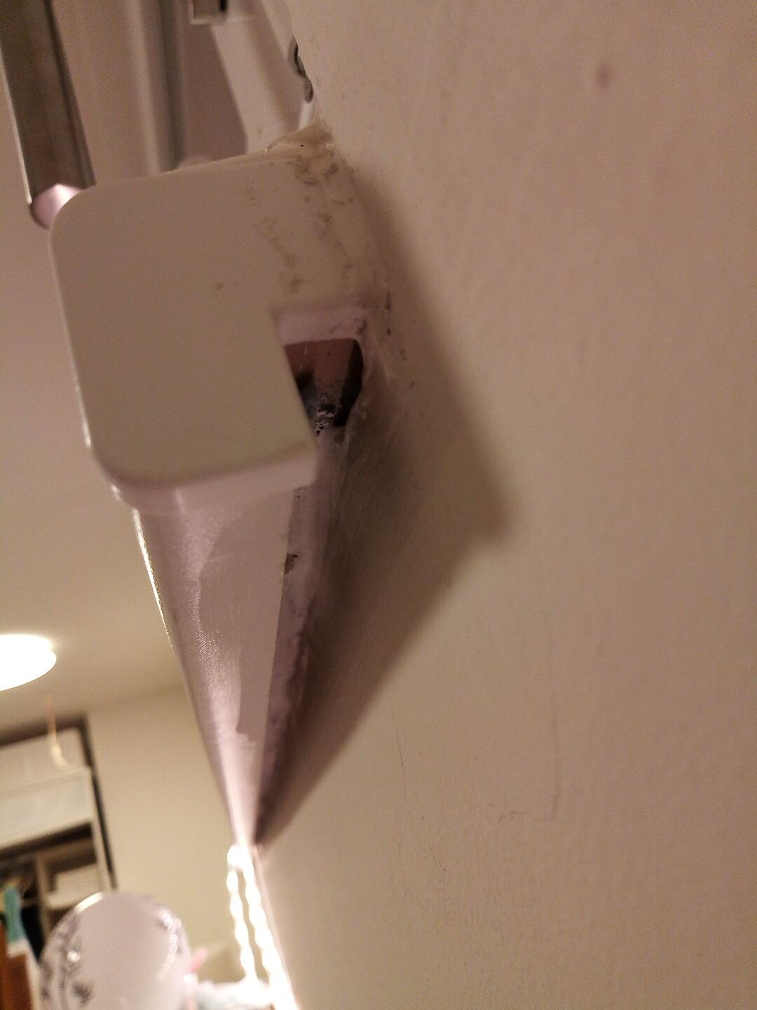 Nahaufnahme eines weißen Türbeschlags an der Wand, unscharfer Hintergrund