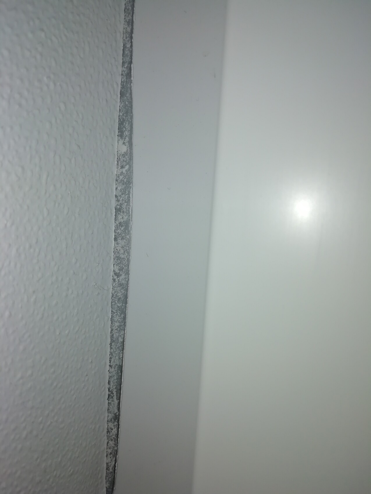 Nahaufnahme eines weißen Türrahmens neben einer strukturierten Wand mit Kanten