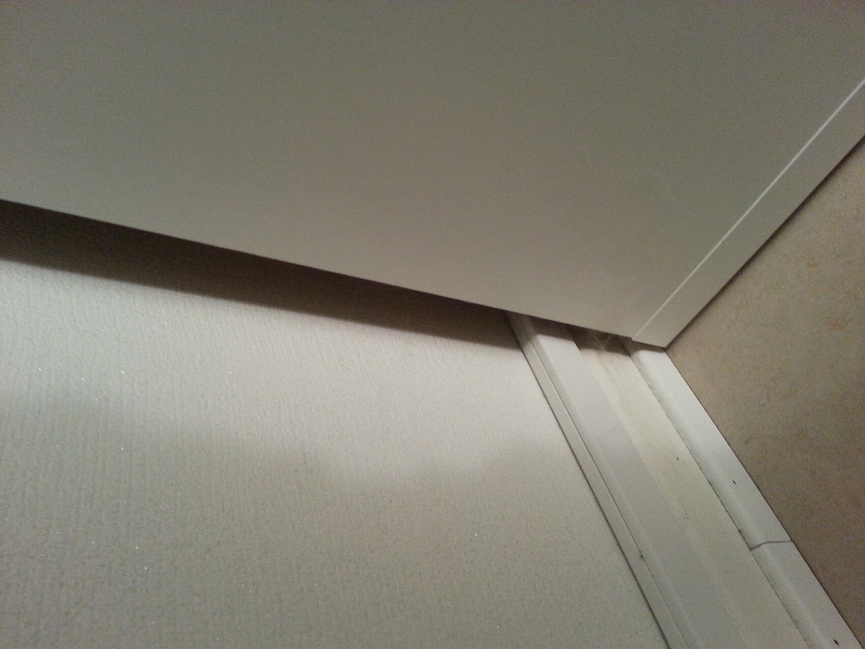 Weiße Türplatte lehnt schräg an einer Wand in einer Raumecke über der Bodenleiste.