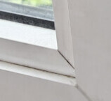 Nahaufnahme eines weißen Fensterrahmens mit Glasscheibe im Innenbereich