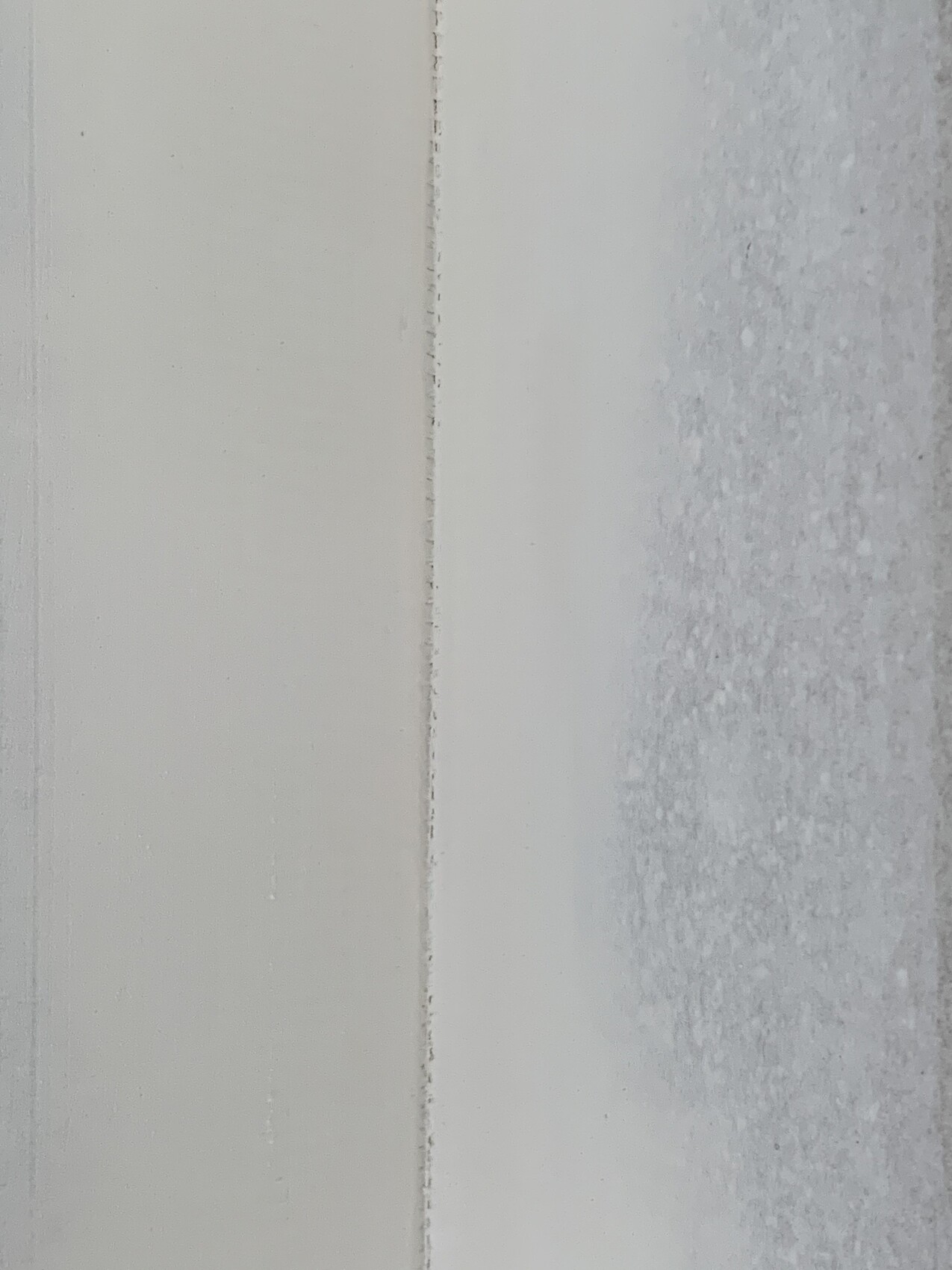 Nahaufnahme eines weißen Türrahmens mit schmaler Fuge; rechts gefrostetes Glas.