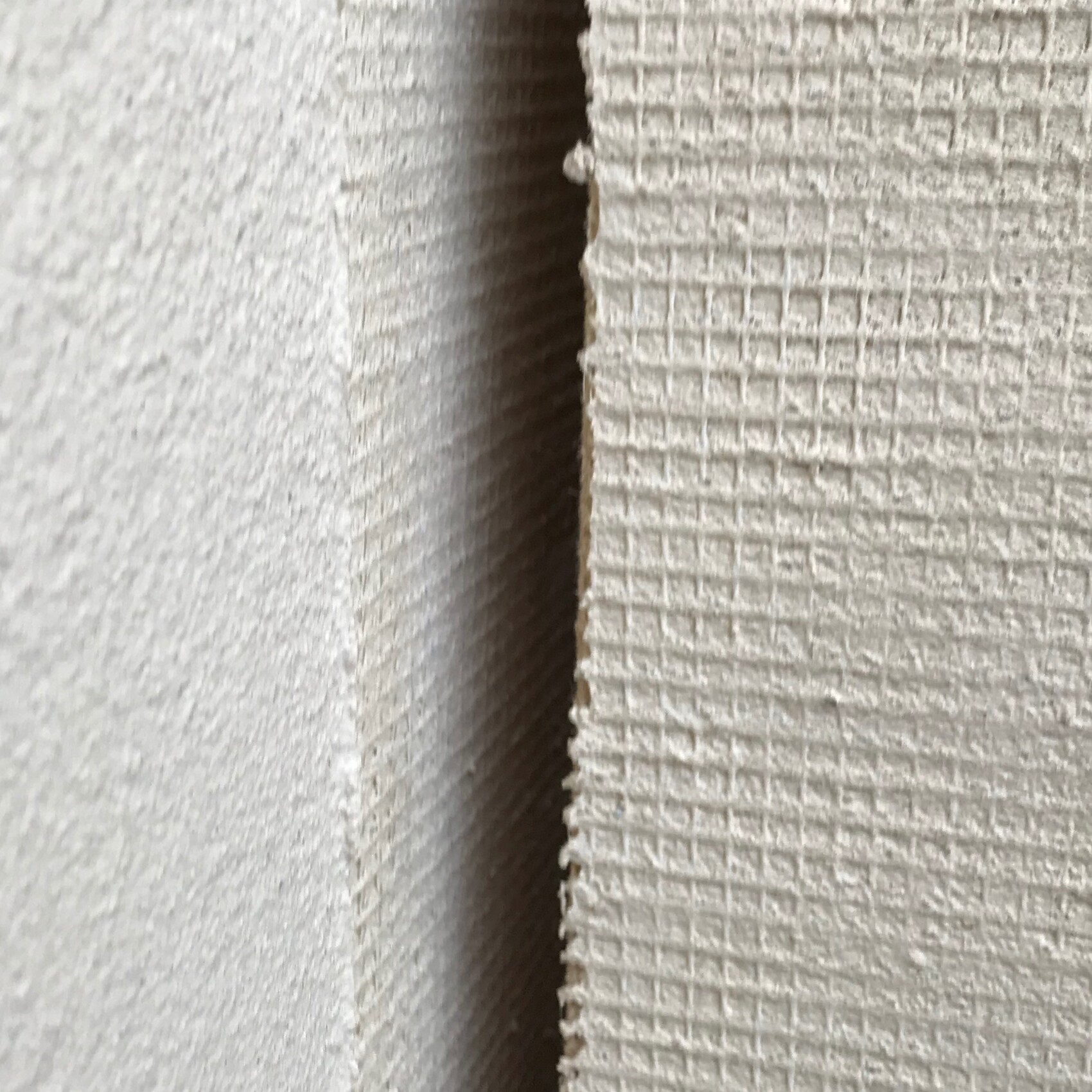 Nahaufnahme einer texturierten Wandoberfläche mit Spalt zwischen zwei Platten.