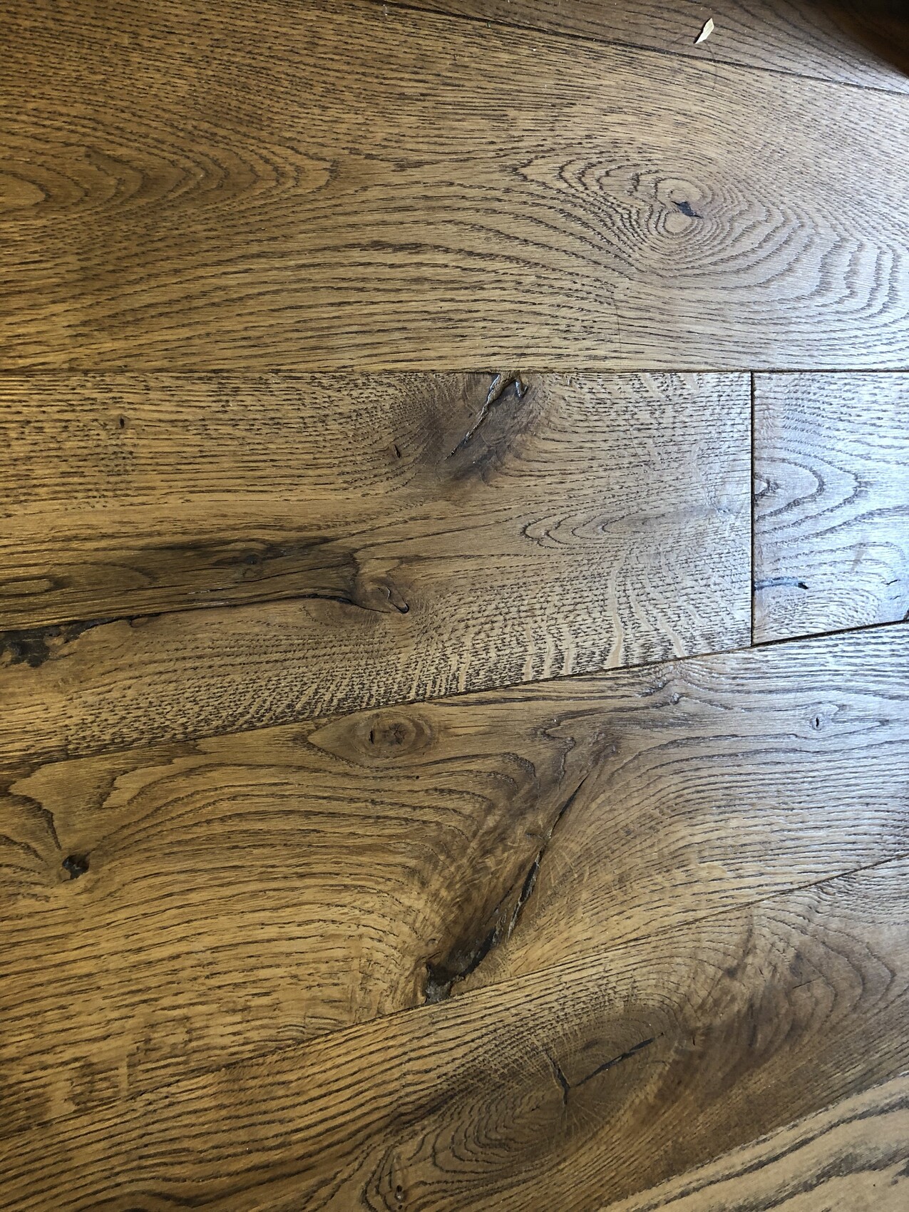 Holzfußboden mit sichtbarer Maserung, Knoten und warmbraunen Tönen.