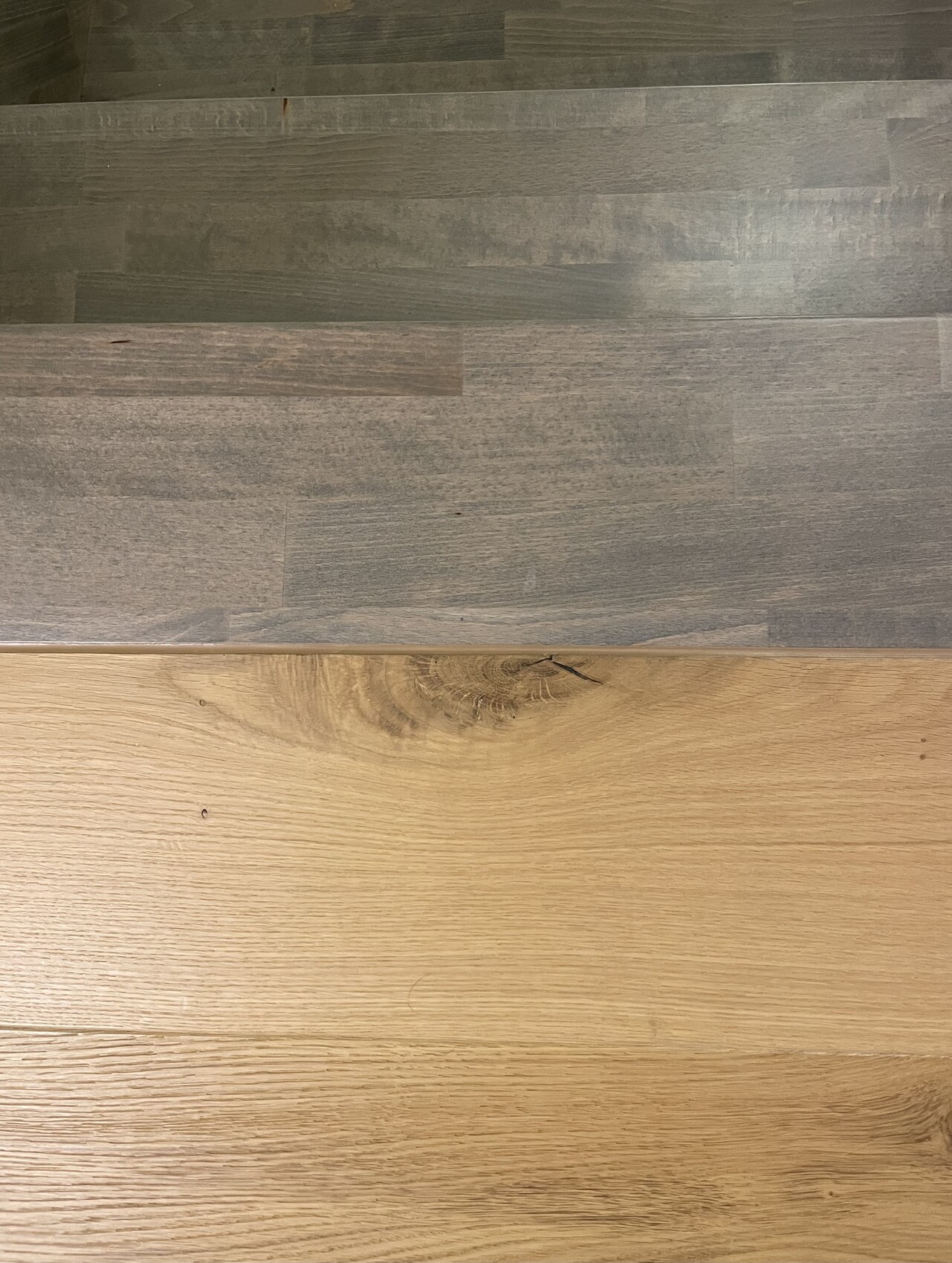 Holzboden mit zwei Abschnitten: oben dunkle graue Planken, unten helles Naturholz.