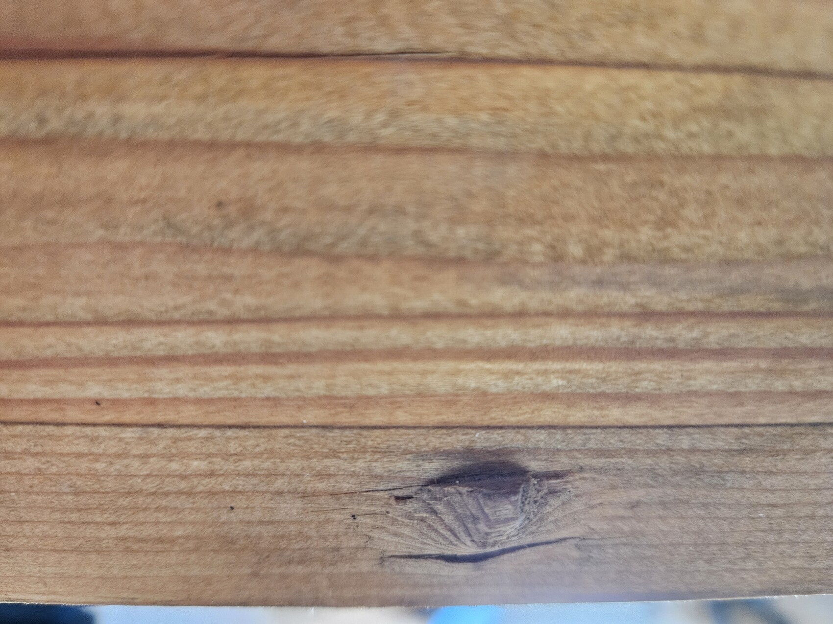 Nahaufnahme von Holzbrettern mit Maserung und einem sichtbaren Knoten in der Holzplatte
