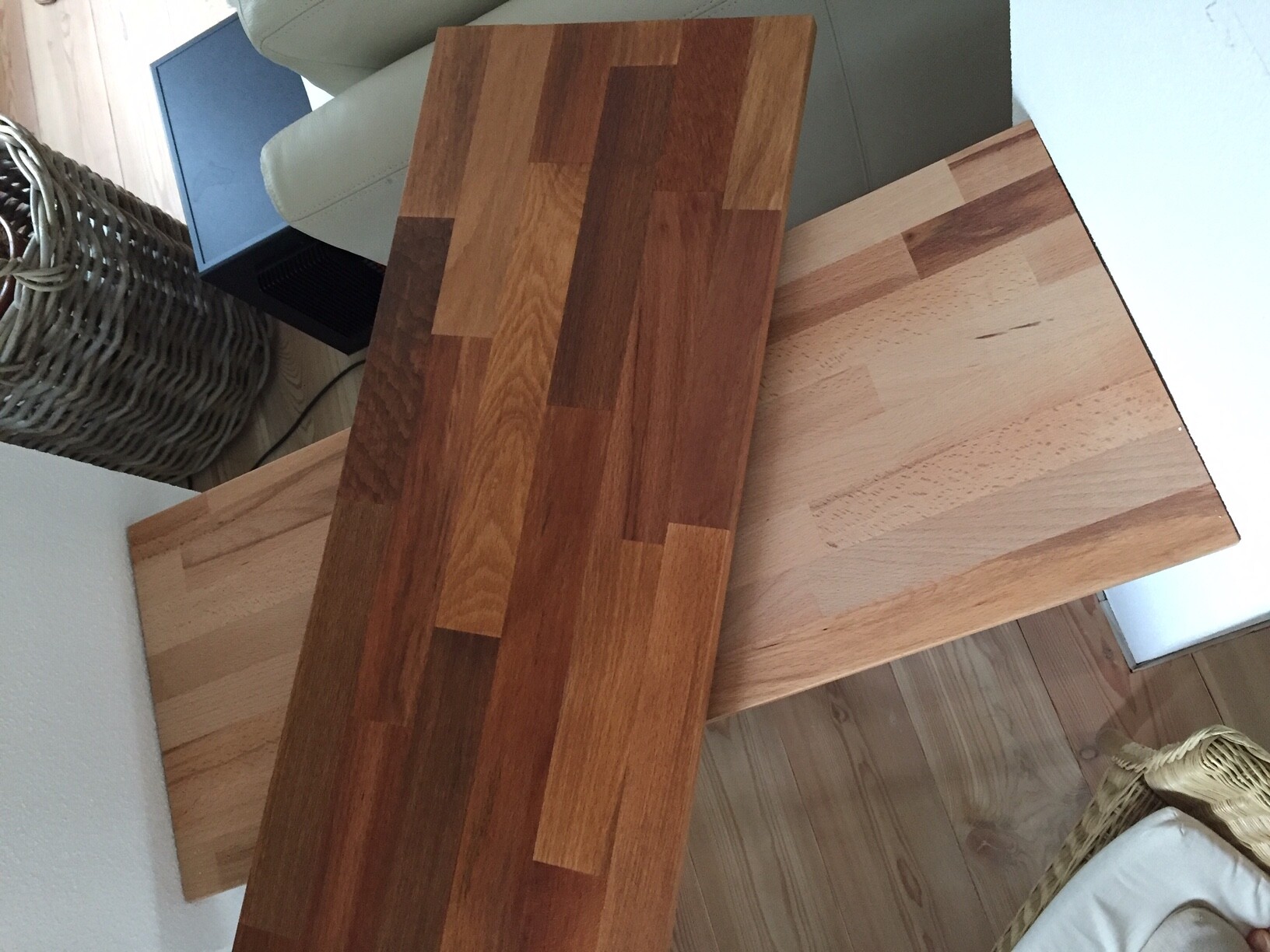 Mehrere Holzbretter unterschiedlicher Holzarten liegen kreuz und quer auf einem Tisch.