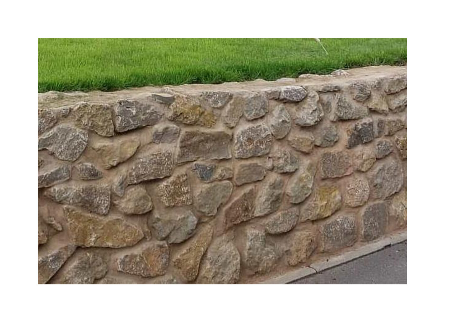 Natursteinmauer am Grasrand neben Gehweg im Garten