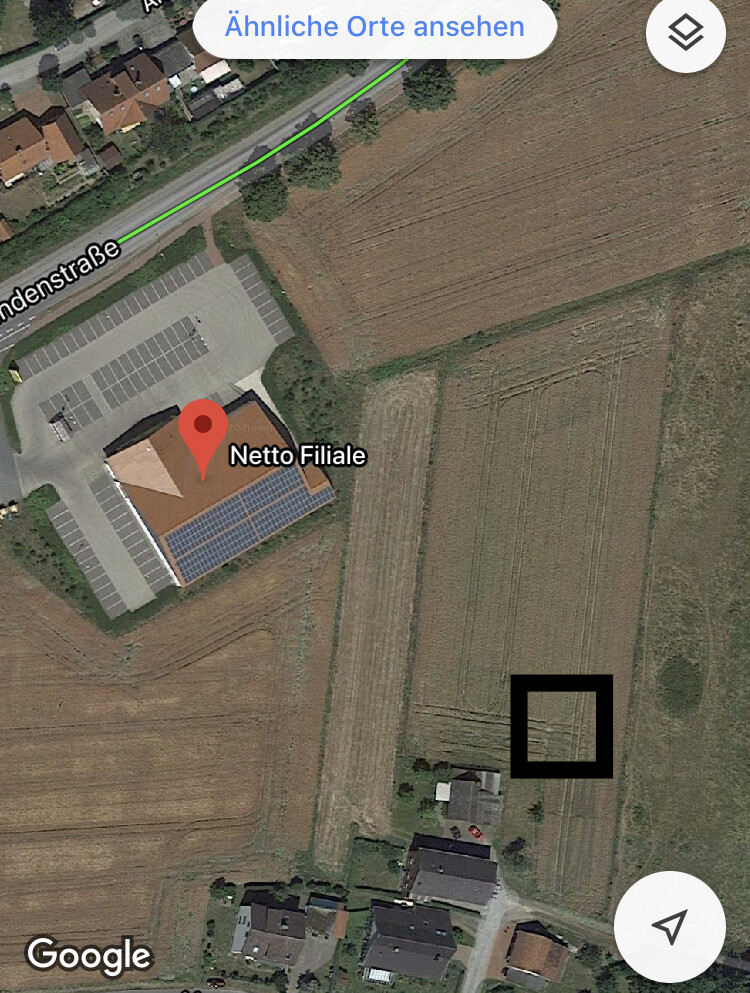 Satellitenaufnahme: Netto-Filiale mit Parkplatz, Solarmodule auf dem Dach, umliegende Felder.