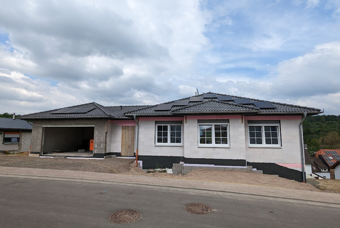 Neubau-Einfamilienhaus mit Solarmodulen auf dem Dach und offener Garage.