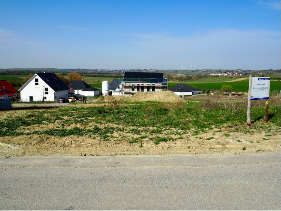 Neubau-Haeuser auf Bauplatz mit Sandhuellen und laendlicher Landschaft