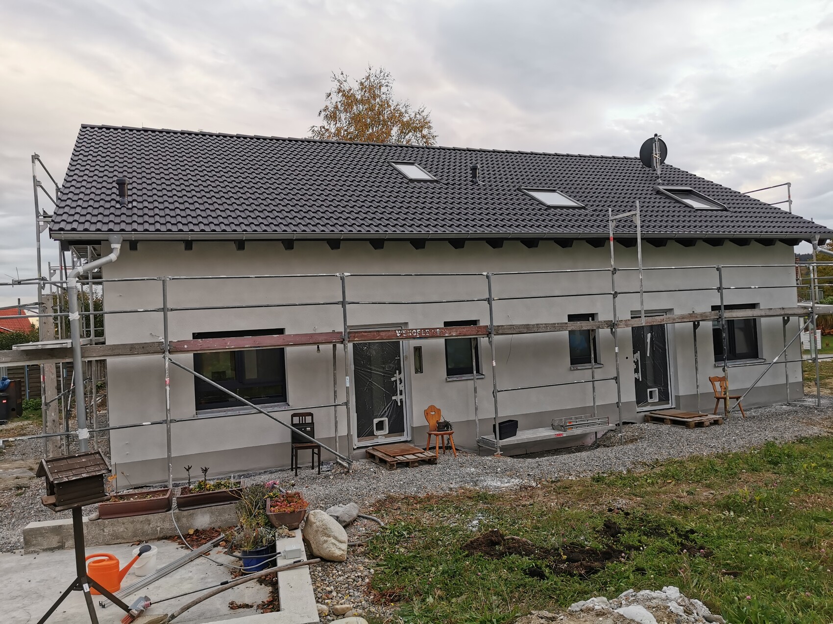 Einfamilienhaus im Bau mit Gerüst, dunklem Ziegeldach, Dachfenstern und Satellitenschüssel