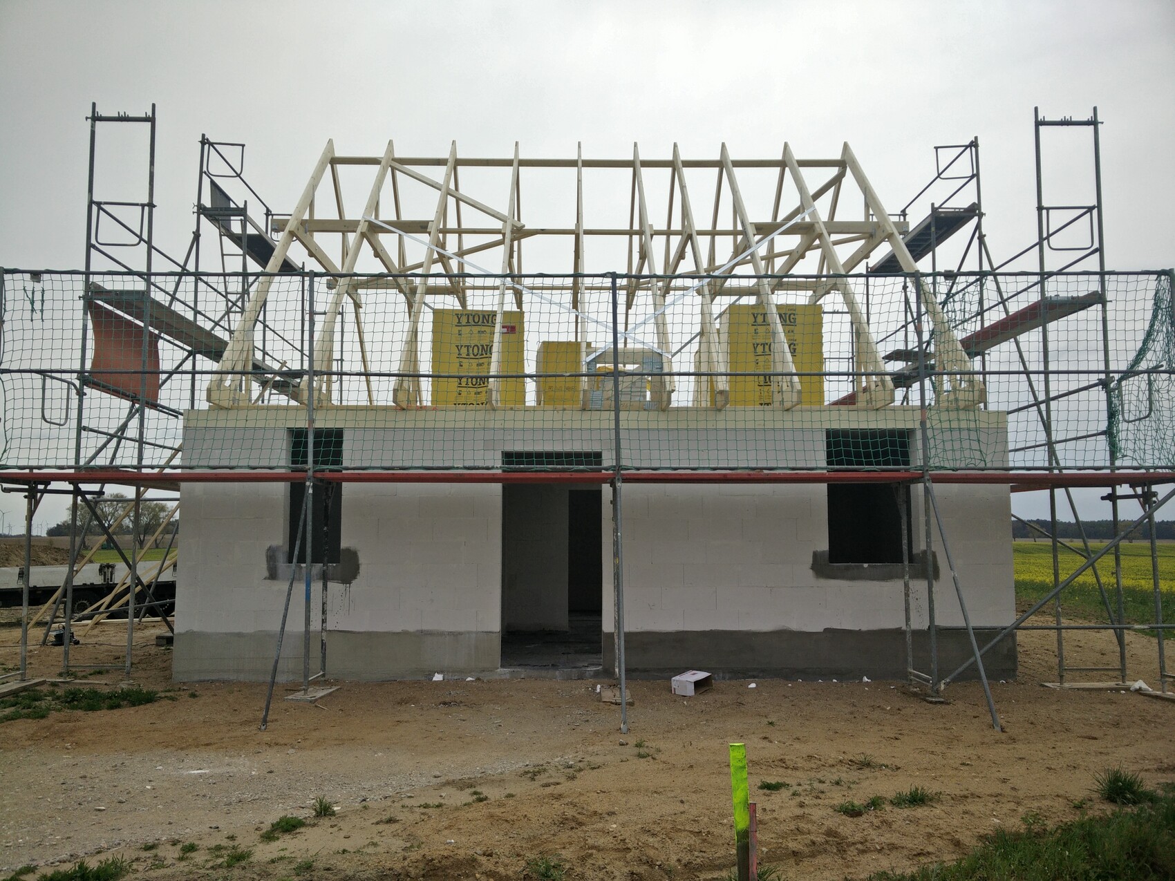 Rohbau eines Hauses mit Holz-Dachkonstruktion, Gerüst und gelben YTONG-Blöcken.