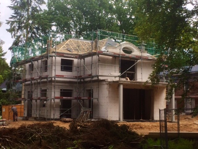 Zweistöckiges Haus im Rohbau mit Gerüst und Dachkonstruktion.