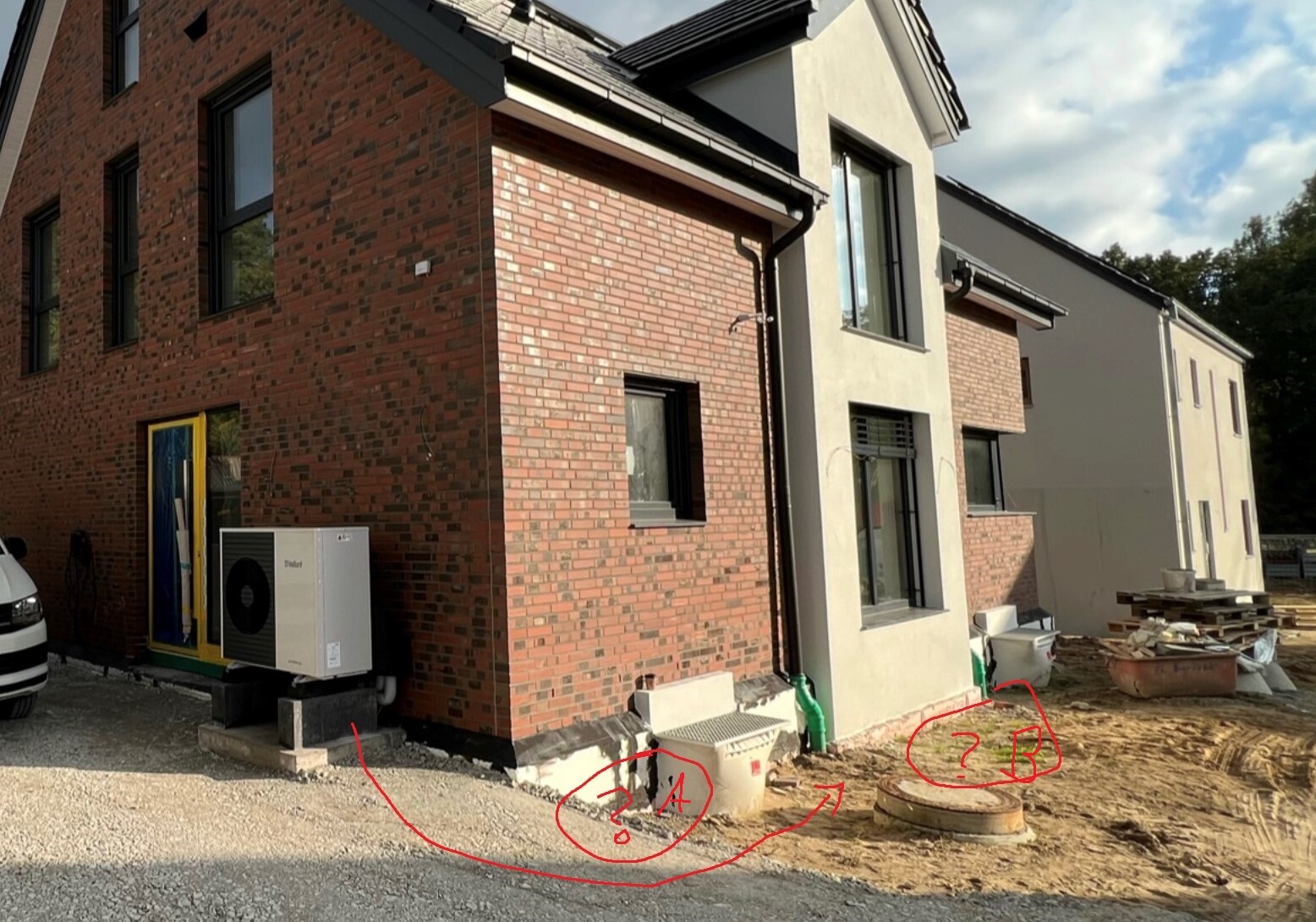 Neubau mit Backstein- und Putzfassade; Außenbereich mit HVAC-Außengerät und Baumaterialien.