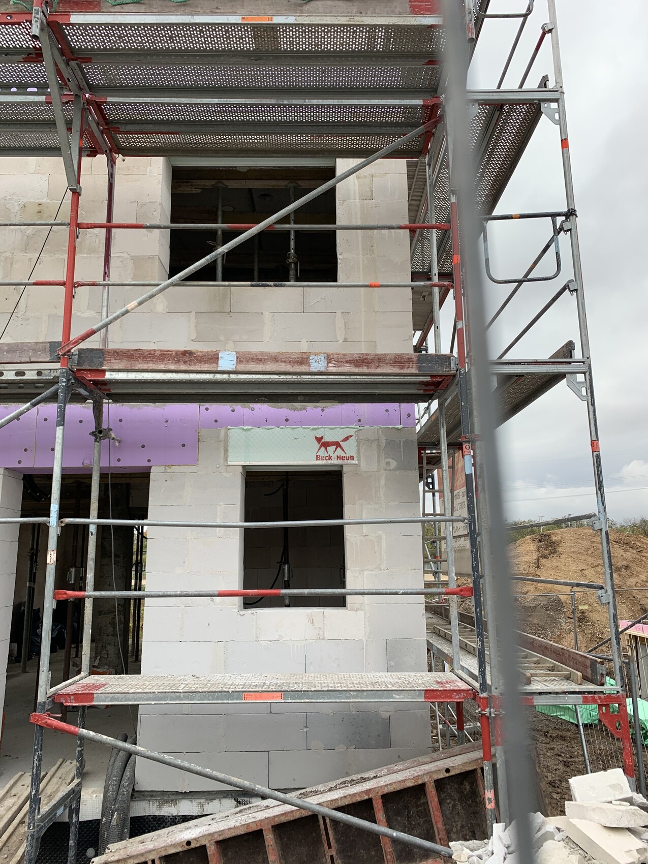 Neubau-Rohbau mit Gerüst, Betonblöcken und offener Fensterlaibung an der Baustelle