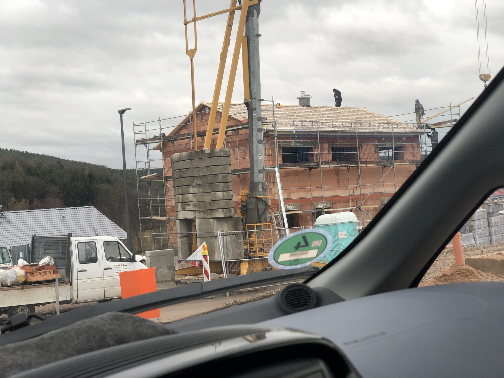 Baustelle: zweistöckiges Backsteinhaus im Bau mit Gerüst, Arbeiter auf dem Dach