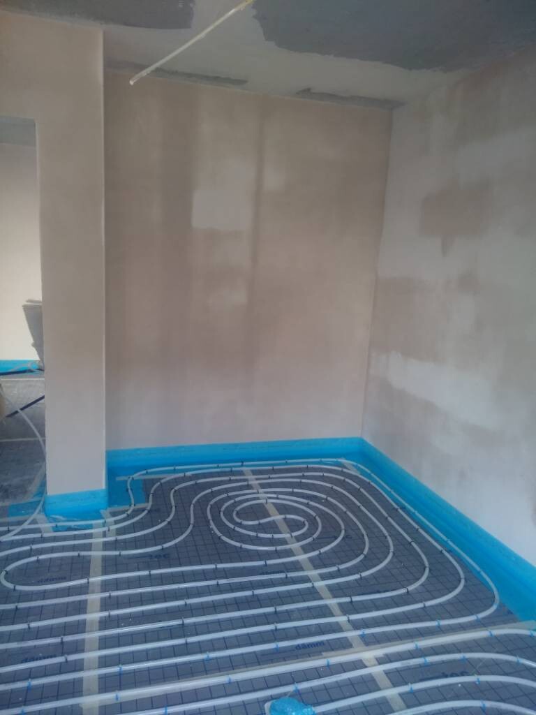 Unterbodenheizung: Spiralrohre im Boden auf Verlege-Netz, Bauzimmer mit blauer Randfolie.