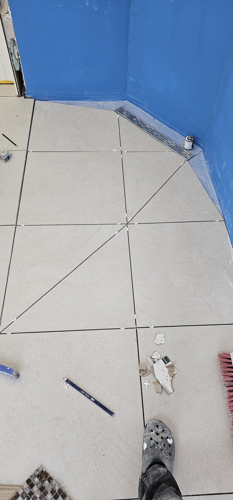 Neue graue Bodenfliesen werden im Badezimmer verlegt, Fliesenabstandhalter sichtbar