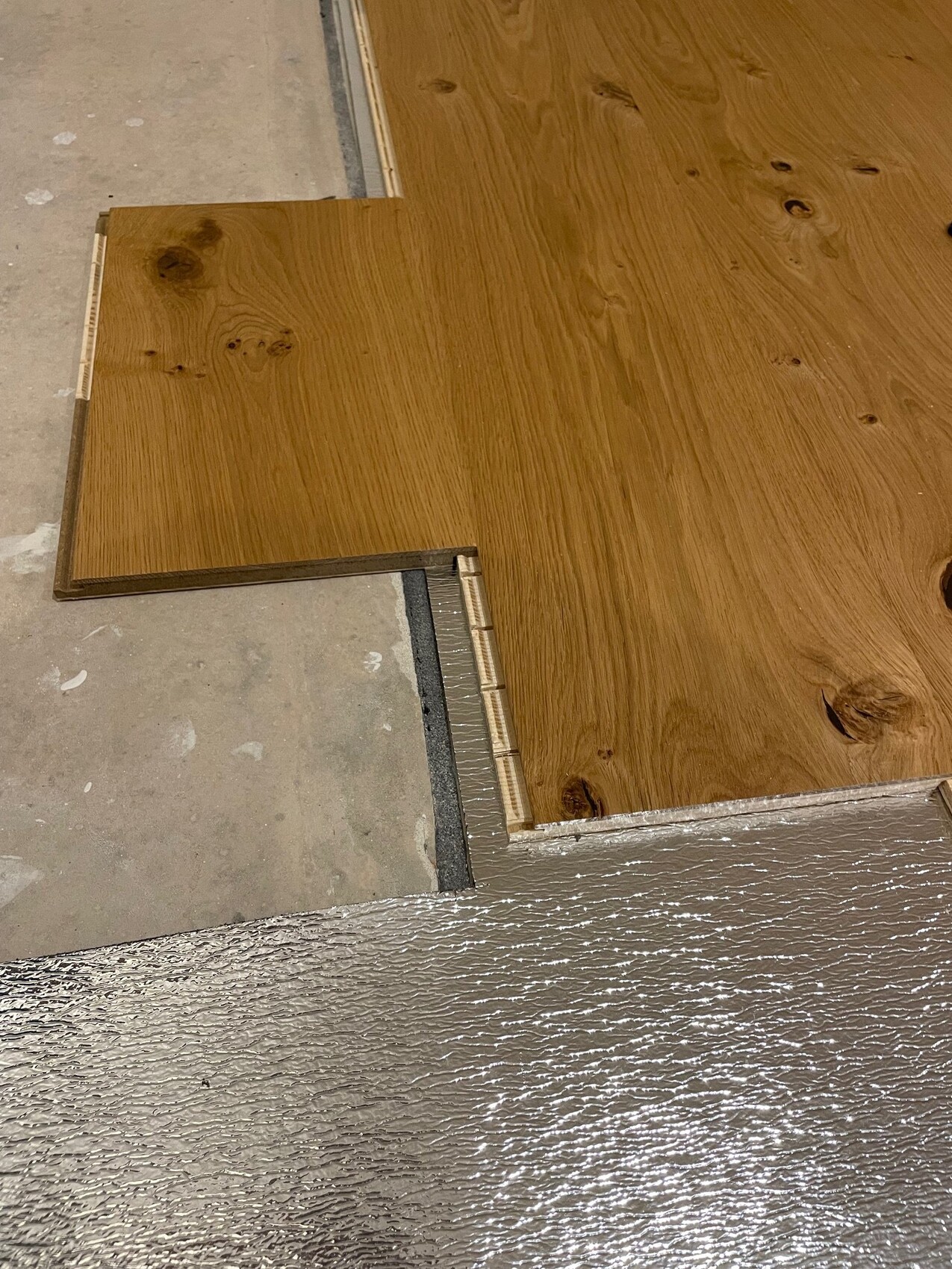 Holzplattenboden auf Unterlage; Übergang mit Metallleiste am Rand sichtbar