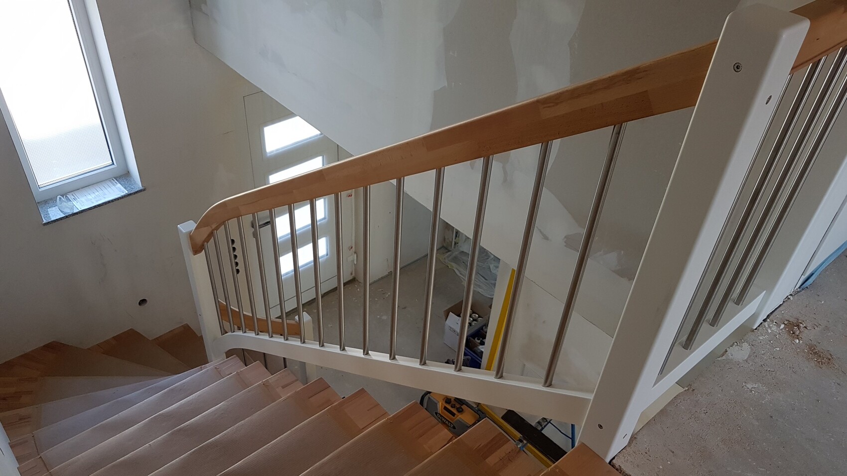 Innenansicht einer Bau-Treppe: Holzstufen, Holzhandlauf, Metallgeländer, Bauwerkzeuge darunter
