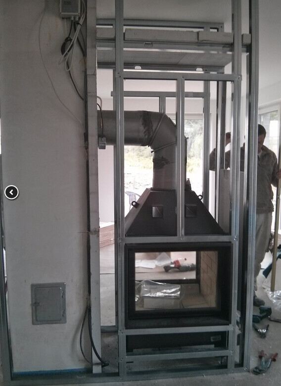 Metallrahmenkonstruktion mit Absaugkanal und Absaugkasten in Innenraum; zwei Personen im Hintergrund.