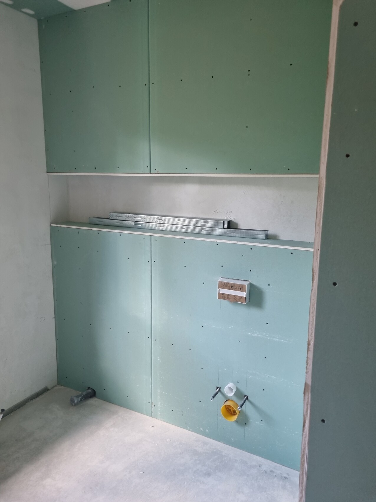 Bauzustand: grüne Gipskartonplatten, Installationen für Spüle unten rechts.