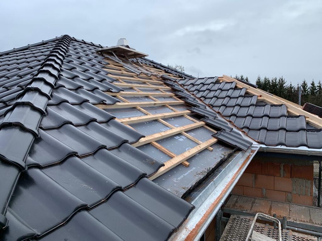 Dach mit dunkelgrauen Ziegeln, teils freiliegende Holzlatten und Dachunterlage.
