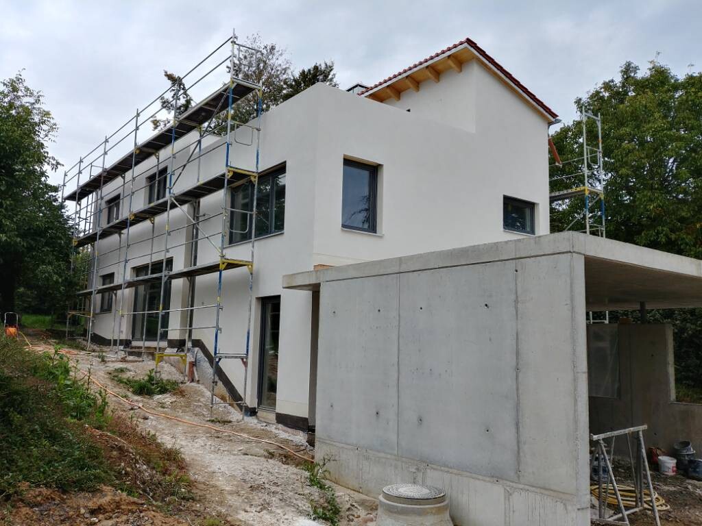 Neues zweistöckiges Haus unter Bau, Gerüst an der Fassade, Betonvorsprung im Vordergrund.