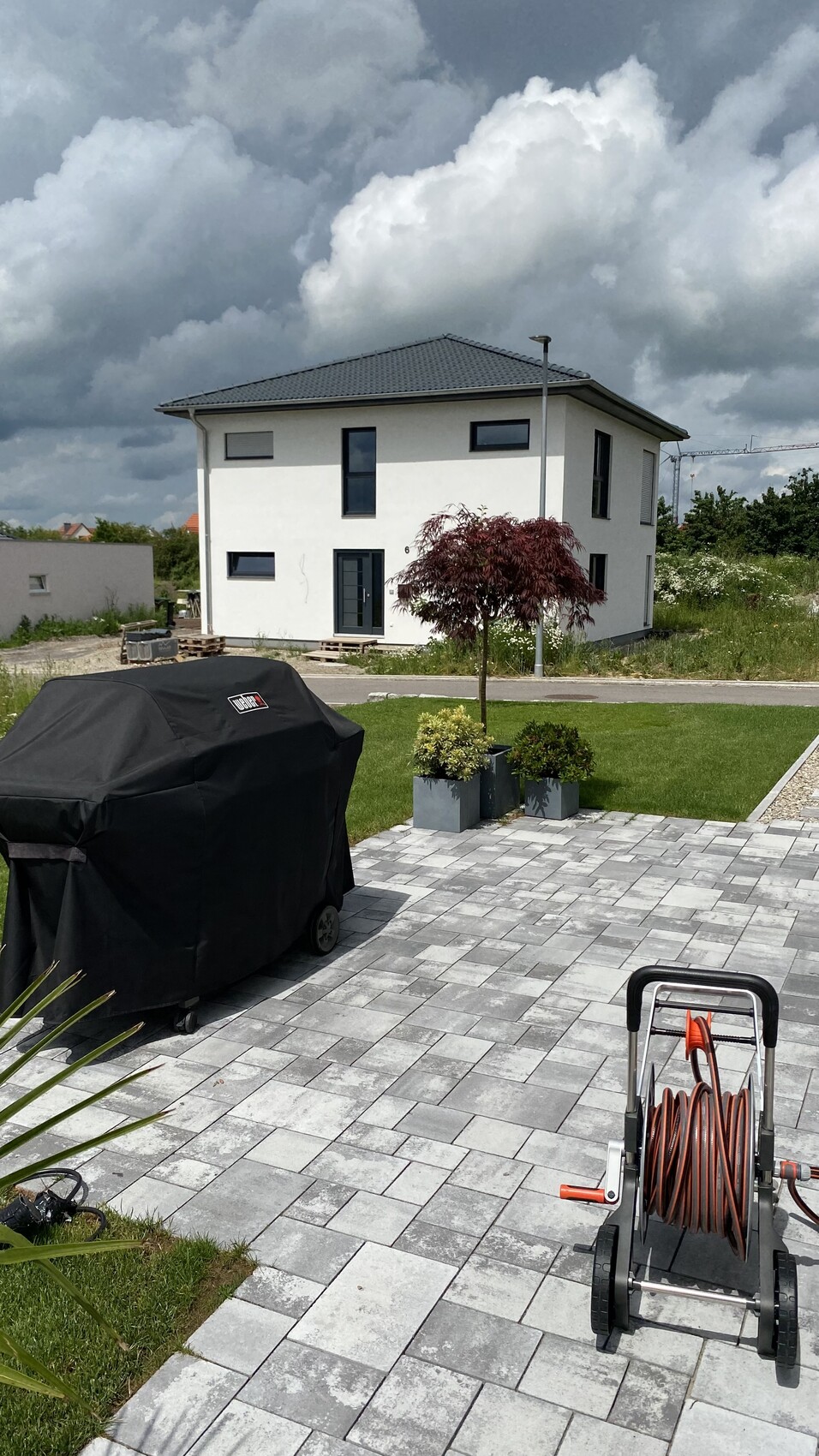 Modernes zweigeschossiges Haus mit gepflasterter Terrasse und Gartenpflanzen