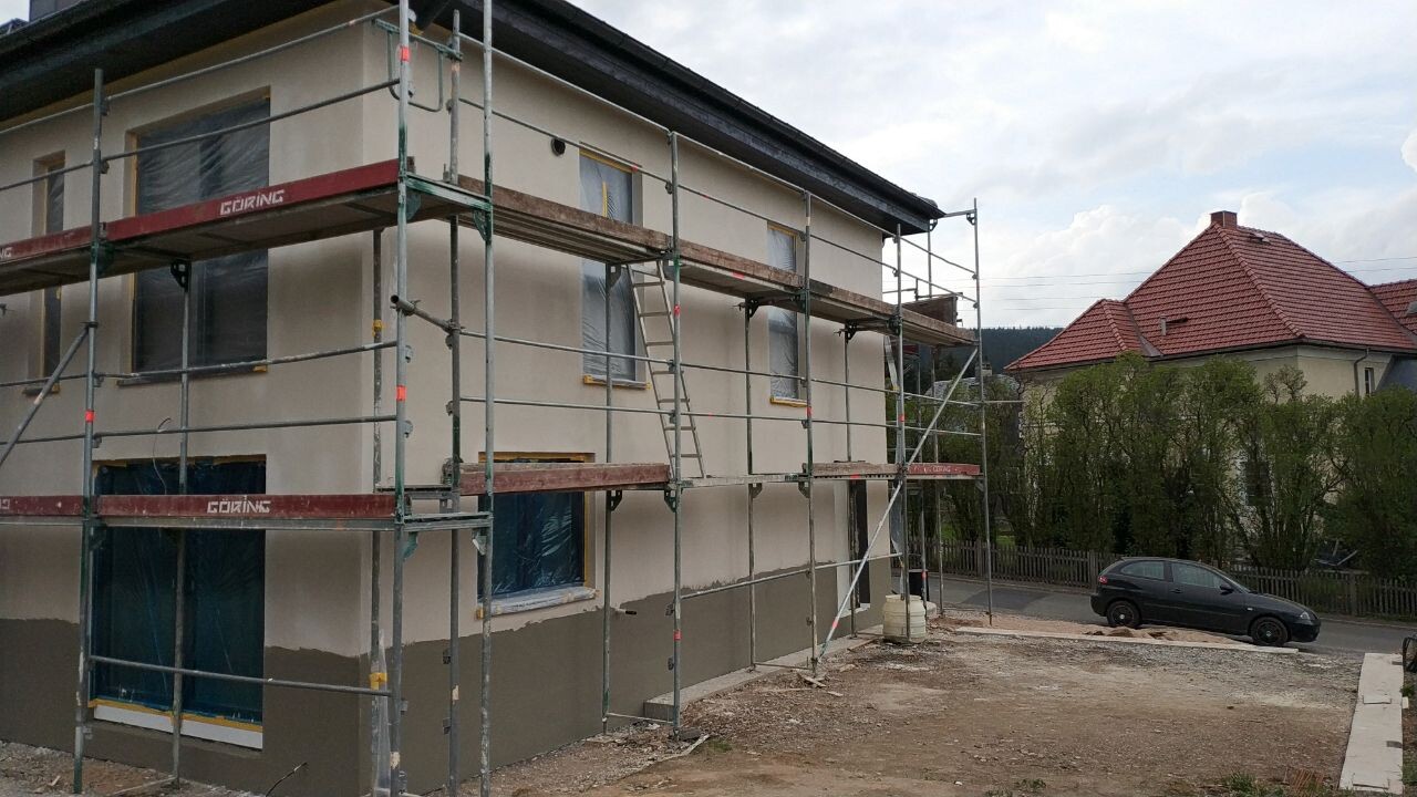 Mehrfamilienhaus unter Renovierung mit Gerüst, Folienfenster; Auto am Straßenrand im Hintergrund