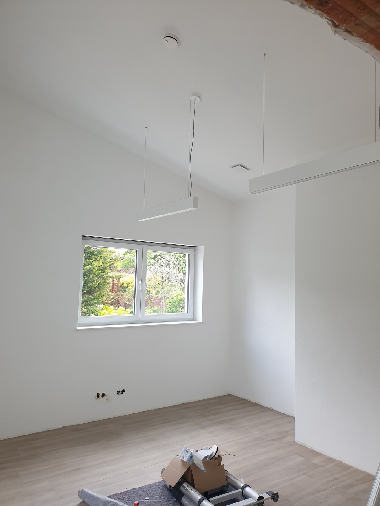 Heller leerer Raum unter Renovierung, hängende Pendelleuchten, Fenster mit Gartenblick