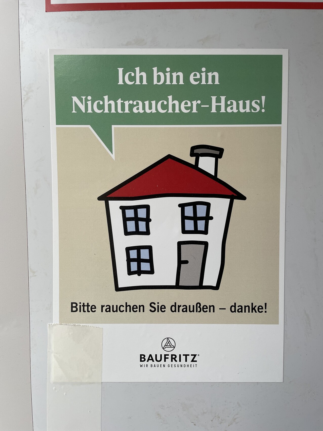 Poster eines Hauses mit grünem Banner 'Ich bin ein Nichtraucher-Haus!'; Bitte draußen rauchen.