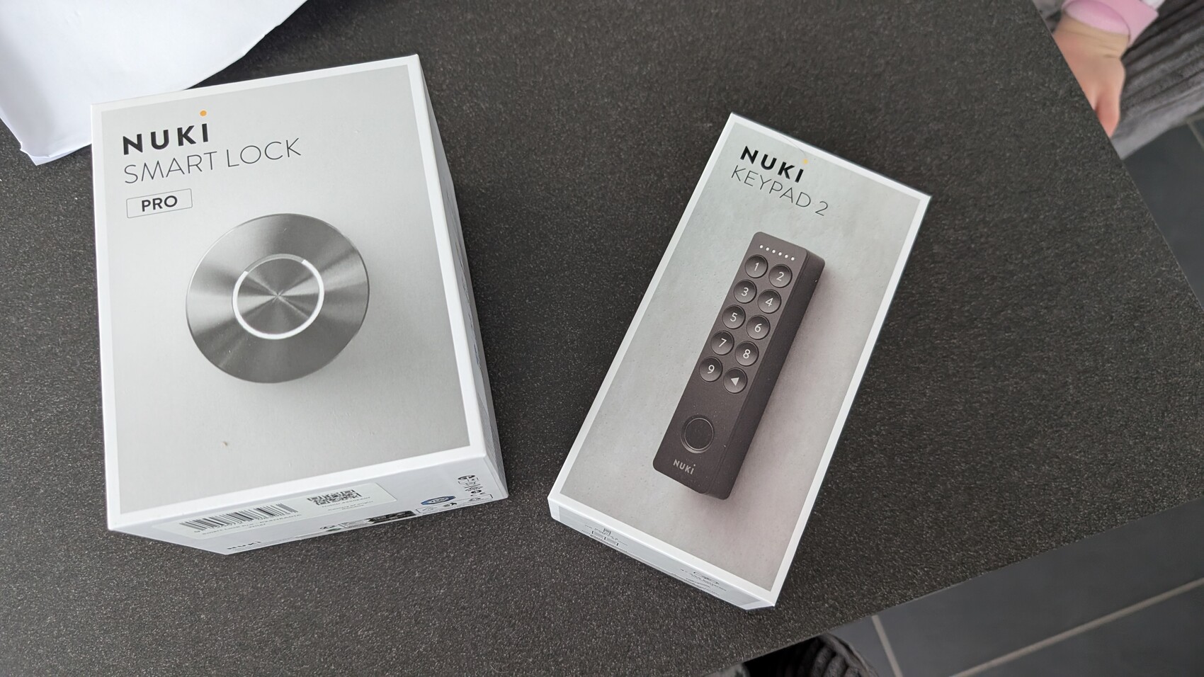 Zwei Nuki-Boxen: Smart Lock Pro und Keypad 2 auf dunklem Tisch