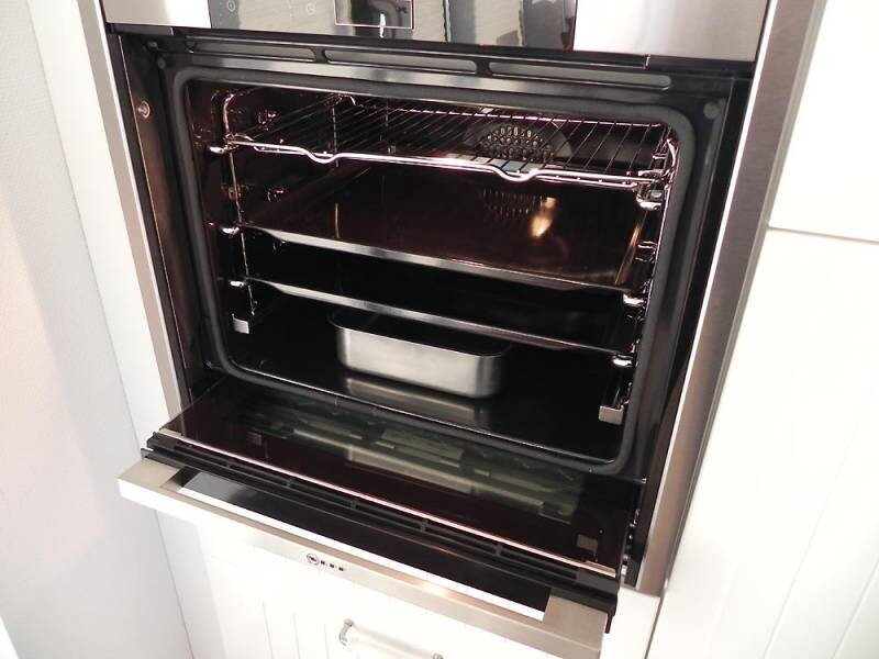 Offener Backofen mit Rost und Backblech in moderner Küche