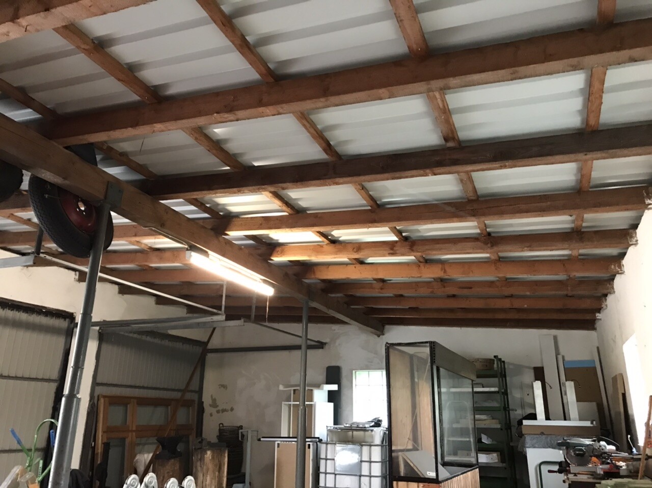 Werkstatt/Lagerraum mit freiliegenden Holzbalkendecken, Regalen und Werkzeugen.