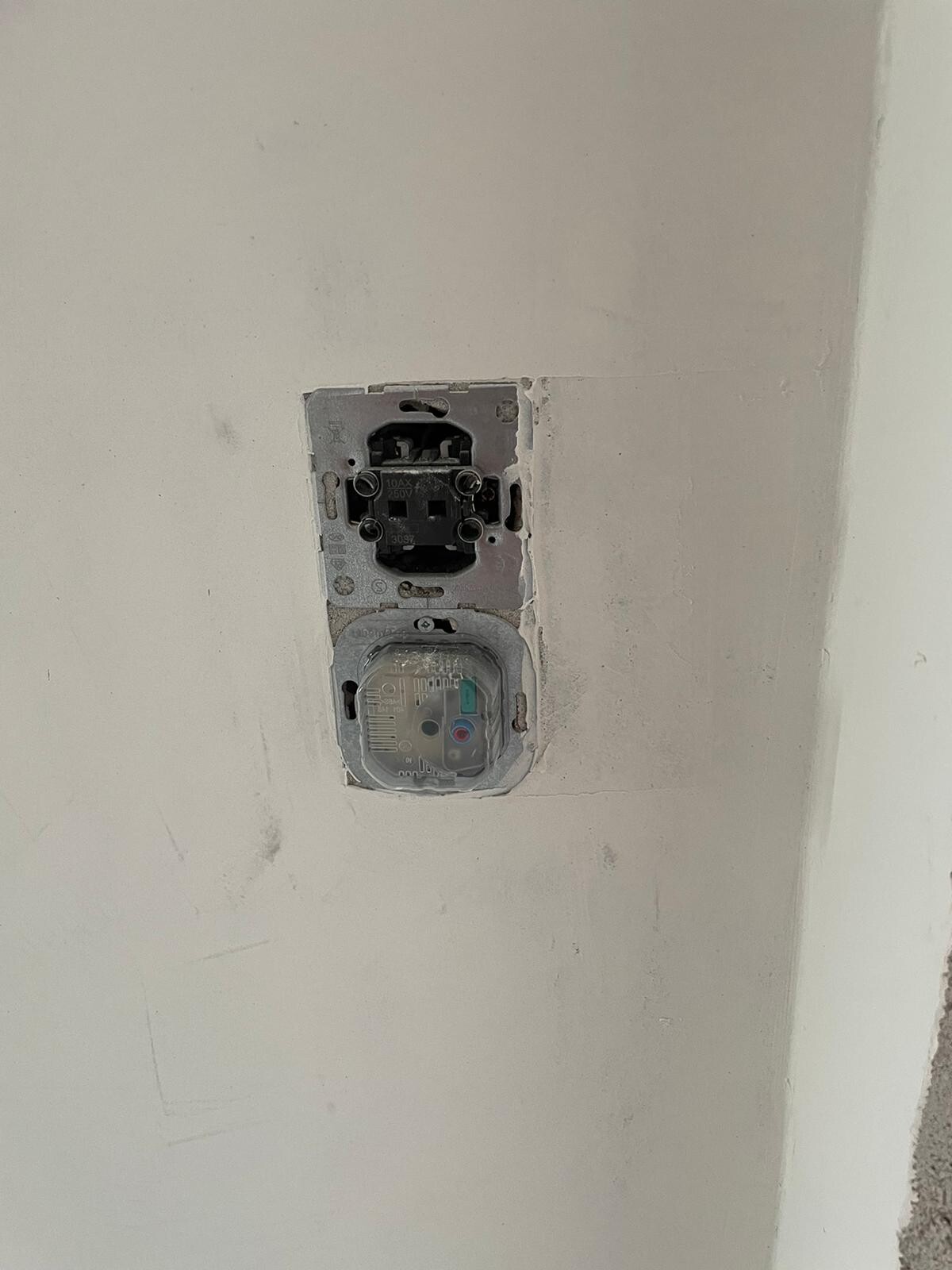 Offene Wandsteckdosen-Installationsdose mit sichtbarer Innenmechanik, Abdeckung fehlt.