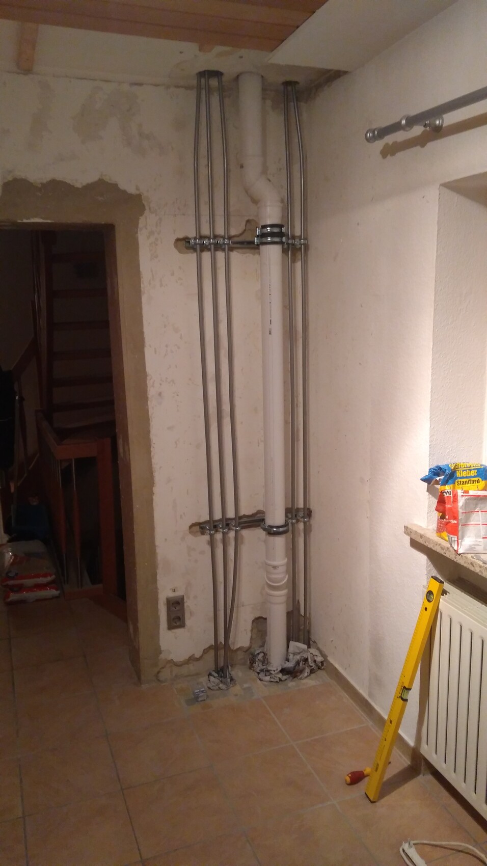 Kellerraum mit weißen PVC-Abflussrohren und Metallrohre an der Wand, Bauarbeiten.