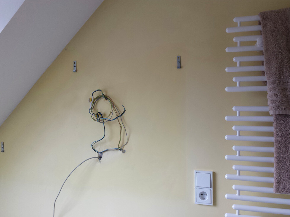Wand mit offenen Kabeln, Steckdose und Heizkörper in Renovierungsraum