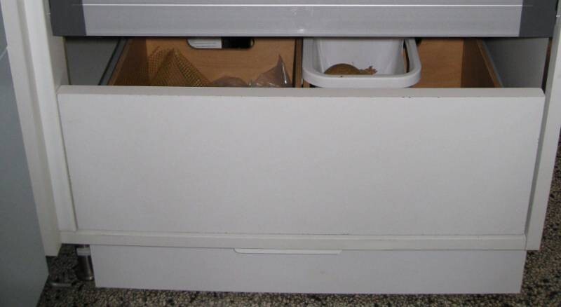 Offene untere Küchen-Schublade eines Geräts mit sichtbaren Gegenständen im Inneren.