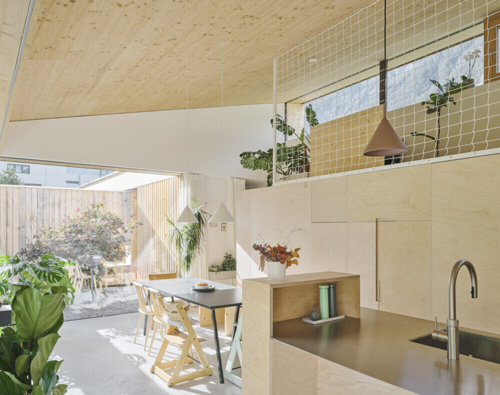 Offene Küche mit Essbereich, Holzkonstruktion, Pflanzen und Blick nach Garten.