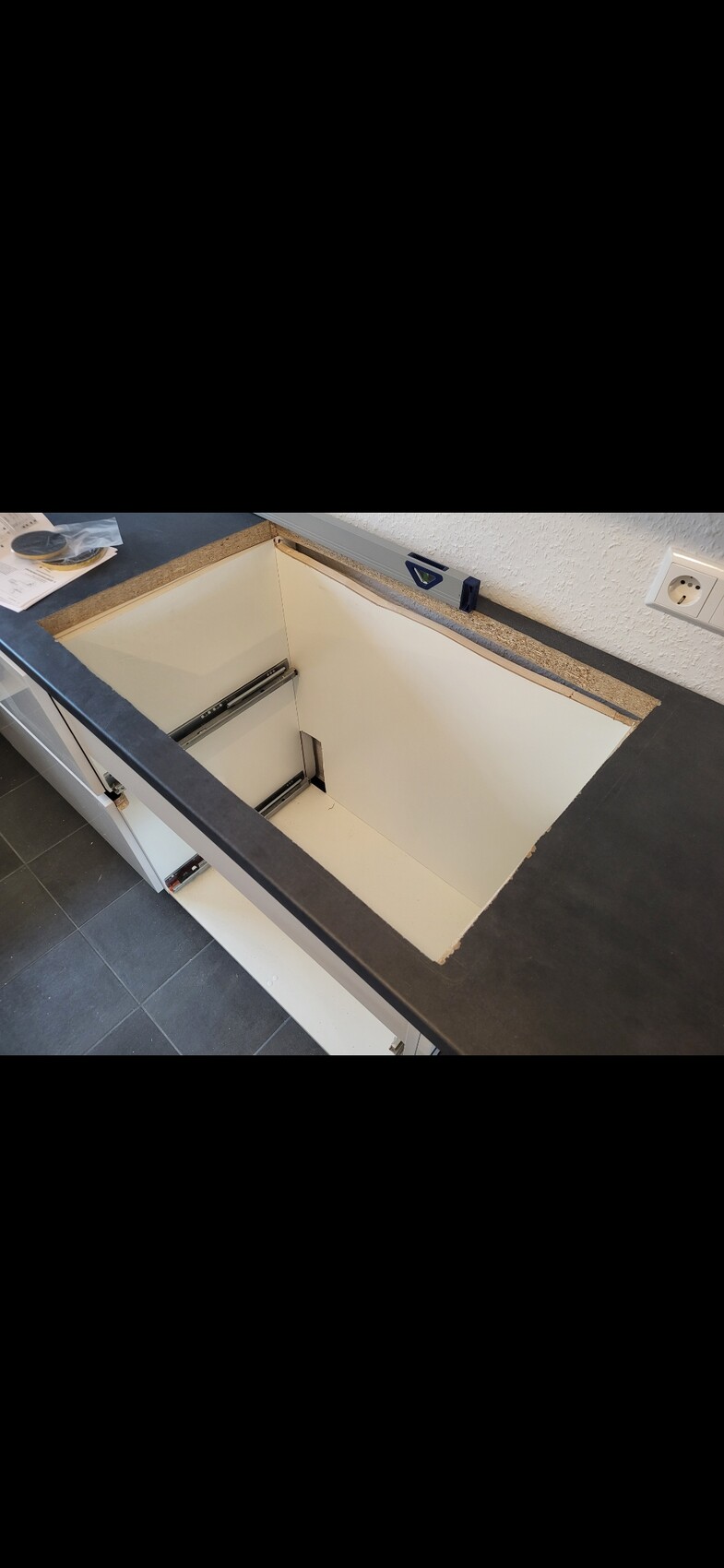 Offener Unterschrank in der Küche mit Führungsschienen und leerem Innenraum.