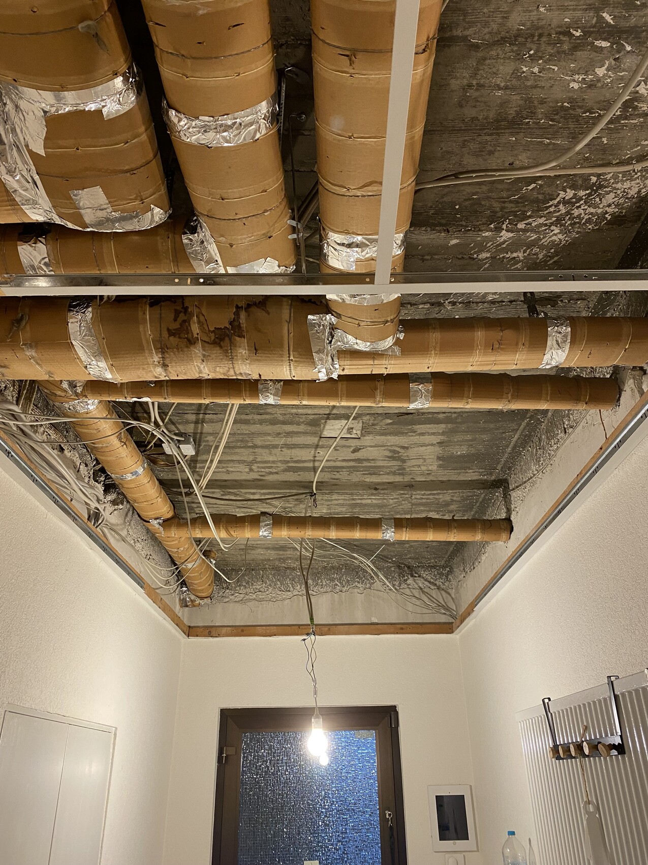 Offene Rohrleitungen und Kabeltrassen hängen von der Decke in einem renovierten Innenraum